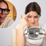 Uma mulher se olha no espelho, chateada com as rugas na testa.