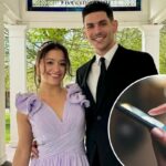 Close das mãos de uma pessoa segurando um smartphone, com um dedo tocando a tela azul.