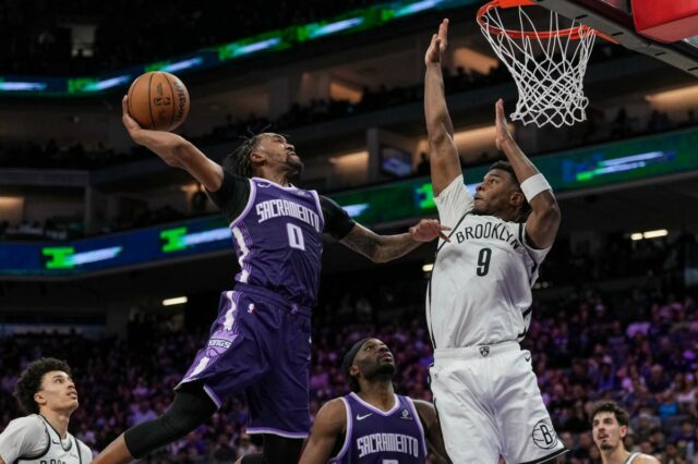 Nets caem para Kings após reviravolta brutal na posse final Malik Monk tenta enterrar para o Sacramento Kings enquanto EJ Liddell do Brooklyn Nets defende.