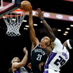 O jogador do Brooklyn Nets, Noah Clowney (21), atirando sobre os jogadores do Sacramento Kings, Devin Carter (22) e Daeqwon Plowden (29).