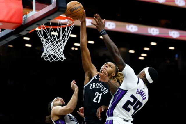 O jogador do Brooklyn Nets, Noah Clowney (21), atirando sobre os jogadores do Sacramento Kings, Devin Carter (22) e Daeqwon Plowden (29).