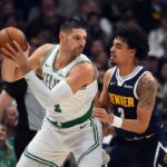 O pivô do Boston Celtics, Nikola Vucevic (4), trabalhou na trave contra o guarda do Denver Nuggets, Julian Strawther (3).