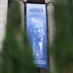 Uma faixa mostrando o presidente Donald Trump está pendurada no Departamento de Justiça, quinta-feira, 19 de fevereiro de 2026, em Washington. (Foto AP/Allison Robbert)