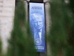 O DOJ dá, o DOJ tira Uma faixa mostrando o presidente Donald Trump está pendurada no Departamento de Justiça, quinta-feira, 19 de fevereiro de 2026, em Washington. (Foto AP/Allison Robbert)