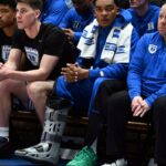O guarda ferido do Duke Blue Devils, Caleb Foster, usando uma bota de caminhada no banco. O guarda ferido do Duke Blue Devils, Caleb Foster (centro), observa usando uma bota de caminhada durante o segundo tempo contra o North Carolina Tar Heels, no Cameron Indoor Stadium.