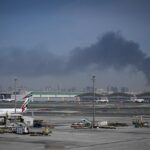 Fumaça sobe do Aeroporto Internacional de Dubai esta manhã enquanto os aviões da Emirates permanecem parados