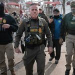 O chefe da patrulha de fronteira dos EUA, Gregory Bovino, segura um rifle enquanto patrulha um bairro de Chicago.