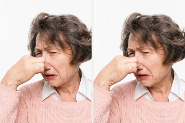 Três mulheres sorrindo em uma mesa de jantar, duas fazendo gestos brincalhões com as mãos. Copos e pratos são colocados na mesa em frente a eles