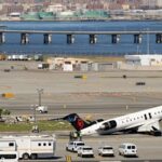 A equipe do aeroporto inspeciona os destroços da aeronave da Air Canada, com os restos do caminhão de bombeiros mostrados à esquerda.