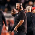 O técnico do Utah, Kyle Whittingham, usando fones de ouvido na linha lateral.