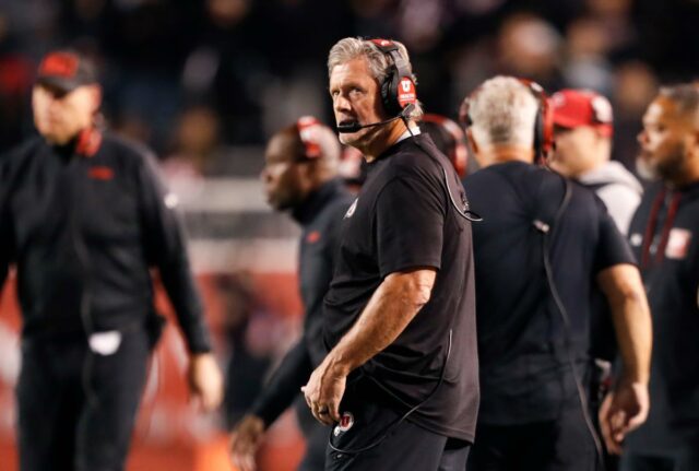 O técnico do Utah, Kyle Whittingham, usando fones de ouvido na linha lateral.