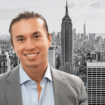 O ex-incorporador imobiliário de Nova York, Joshua Schuster, admite fraude de investidores e esquema de perdas em jogos de azar. Foto de Joshua Schuster, sorrindo em um terno cinza e camisa azul claro, posado em frente ao horizonte preto e branco da cidade de Nova York com o Empire State Building.