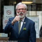 O ex-presidente do Sinn Fein, Gerry Adams, levanta o polegar ao chegar para seu histórico julgamento civil
