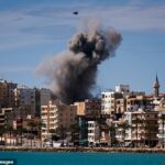 Uma nuvem de fumaça e um fragmento de concreto sobem do local de um ataque aéreo israelense na periferia leste de Tiro, no sul do Líbano, em 24 de março.