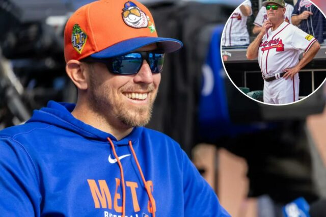 O técnico de rebatidas do New York Mets, Troy Snitker, sorrindo enquanto usava um boné de beisebol laranja e azul e um moletom azul.