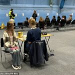 Alunos recebendo vacinas e antibióticos da equipe médica no pavilhão esportivo do campus da Universidade de Kent, em Canterbury