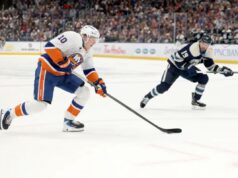 Os ilhéus aparentemente encontraram o segredo do sucesso na prorrogação O jogador do New York Islanders, Simon Holmstrom, patina no gelo com seu taco de hóquei, enquanto o jogador do Columbus Blue Jackets, Cole Sillinger, patina atrás dele.