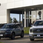 Vista lateral dos novos Ford Mustangs e outros modelos Ford estacionados em frente à concessionária Ford no Texas.
