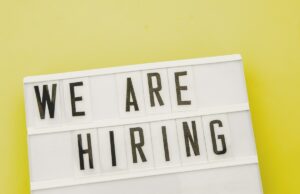 Os tokens de IA são o novo bônus de assinatura ou apenas um custo para fazer negócios? We Are Hiring sign, used in post about Weekday