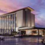 Penn Entertainment marca inauguração em junho para estreia no hotel Hollywood Casino Columbus. Torre de hotel moderna de vários andares no Hollywood Casino Columbus com fachada de vidro, entrada coberta e carros chegando ao anoitecer sob um céu colorido do pôr do sol.