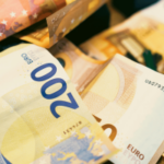 A polícia espanhola desmascarou uma rede de lavagem de dinheiro de jogos de azar que explorava refugiados de guerra ucranianos. Grande plano de notas e moedas de euro dispersas, com uma nota de 200 euros bem visível em primeiro plano.