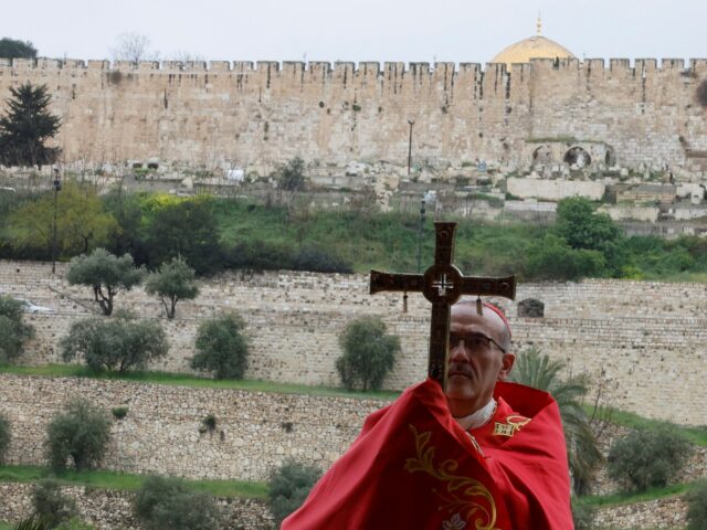 Cristão palestino que é popular por ser o Papai Noel da cidade, segura uma cruz e uma palma na frente enquanto fica nas portas da Igreja do Santo Sepulcro após encontrá-las trancadas