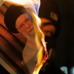 Um manifestante queima uma imagem de Ali Khamenei durante um protesto em frente à Embaixada do Irã em 14 de janeiro.