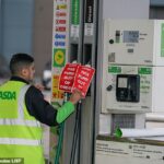 Um trabalhador afixa uma placa em bombas quebradas em um posto de gasolina Asda em Manchester, Grande Manchester