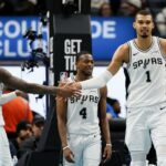 O armador do San Antonio Spurs, Devin Vassell, à esquerda, comemora com o atacante Victor Wembanyama (1) após marcar contra o Detroit Pistons durante o segundo tempo de um jogo de basquete da NBA na segunda-feira, 23 de fevereiro de 2026, em Detroit.