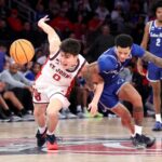 O técnico do St. John's Red Storm, Rick Pitino, reagindo a uma chamada, com dois jogadores do St.