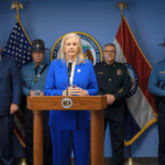 O procurador-geral do Missouri fala em conferência de imprensa sobre a repressão às máquinas de jogo ilegais com autoridades policiais e bandeiras estaduais atrás do pódio