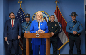 Procurador-geral do Missouri registra acusações contra loja local em caso de máquinas de jogo ilegais O procurador-geral do Missouri fala em conferência de imprensa sobre a repressão às máquinas de jogo ilegais com autoridades policiais e bandeiras estaduais atrás do pódio