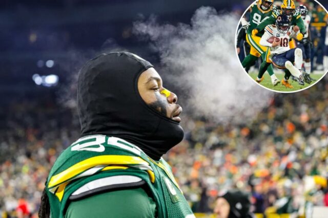 O lado defensivo do Green Bay Packers, Rashan Gary, exala, com respiração visível no ar frio, enquanto veste uma balaclava preta e uma camisa verde.