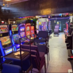 Interior de uma sala de jogos ilegais em San Antonio com fileiras de caça-níqueis, cadeiras e luzes de neon durante invasão no condado de Bexar