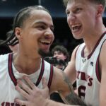 O guarda do Saint Mary, Mikey Lewis (0), vai para a cesta contra o guarda do Gonzaga, Mario Saint-Supery, à direita, durante o segundo tempo de um jogo de basquete universitário da NCAA em Moraga, Califórnia, sábado, 28 de fevereiro de 2026. (AP Photo / Tony Avelar)