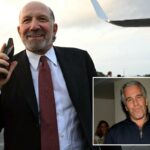 O secretário de Comércio dos EUA, Howard Lutnick, segurando um telefone e sorrindo ao embarcar no Força Aérea Um.