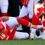 O quarterback do Kansas City Chiefs, Patrick Mahomes, segura o joelho machucado no chão durante um jogo.