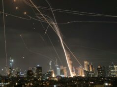 Terroristas do Hezbollah lançam 100 foguetes contra Israel – esmagando a Cúpula de Ferro Foto de longa exposição de mísseis e seus interceptadores no horizonte de uma cidade à noite.