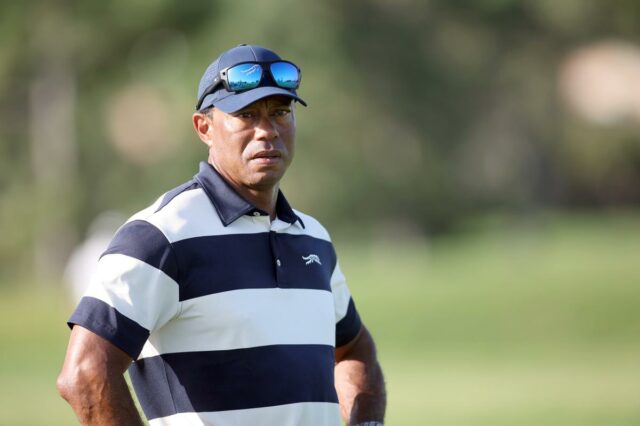Tiger Woods envolvido em acidente de carro capotado na Flórida Tiger Woods em uma camisa pólo listrada de azul e branco e boné azul com óculos escuros.