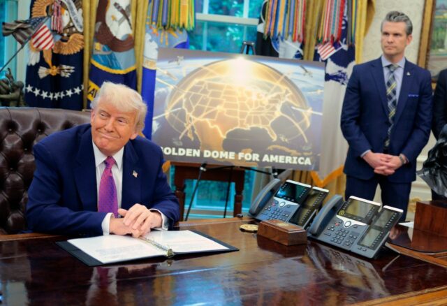 Golden Dome missile program placard with Trump sitting at desk