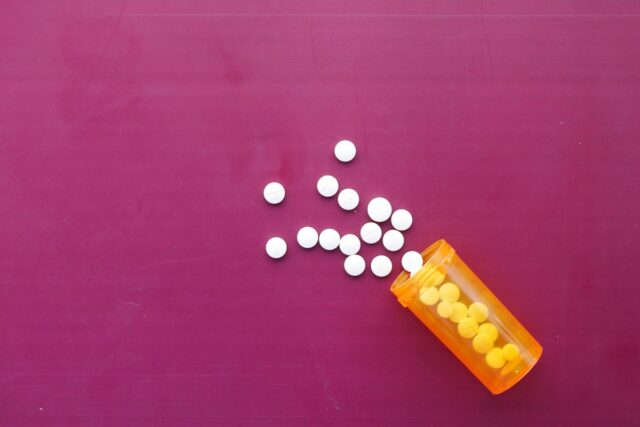 white color medical pills spilling on pink ,