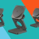 Um smartphone exibindo um calendário e um relógio em um suporte de carregamento ao lado de um laptop, fones de ouvido sem fio e um smartwatch.