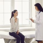 Uma jovem com uma longa trança e um suéter cinza tosse em sua mão.