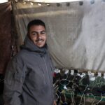 Abdel Karim Salman dirige-se diariamente à estação de carregamento para carregar o seu telefone e o telefone da sua esposa, que eles usam como fonte de luz na sua tenda durante toda a noite (Abdelhakim Abu Riash/Al Jazeera)