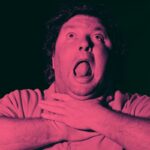 Um homem de cabelos cacheados é mostrado com a boca bem aberta e os olhos voltados para cima, segurando a garganta com as duas mãos, como se estivesse sufocando ou lutando para respirar. A imagem tem uma forte tonalidade vermelho-rosada e um fundo escuro.