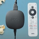 A caixa de streaming Onn em uma mesa de madeira ao lado do controle remoto.