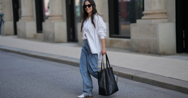FRANKFURT AM MAIN, ALEMANHA - 26 DE MARÇO: Julia Kammerer é vista vestindo uma manga longa de algodão listrada horizontal rosa e bordô oversized da H&M; uma camisa de botão listrada azul e branca amarrada na cintura da JJXX; jeans de perna larga azul claro com corte descontraído da JJXX; tênis com cadarço de couro texturizado bordô e amarelo da Adidas; uma grande bolsa hobo de couro tecido cor de vinho da NA-KD; um boné de beisebol rosa claro com texto bordado em vermelho 