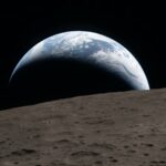 O Comandante Reid Wiseman olha para a Terra pela janela de uma cabine.