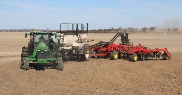 A concessionária de máquinas está transportando grandes armas para a colheita comunitária de uma cidade
