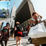 Uma mulher passa pela vitrine de uma loja de varejo com cinco manequins.